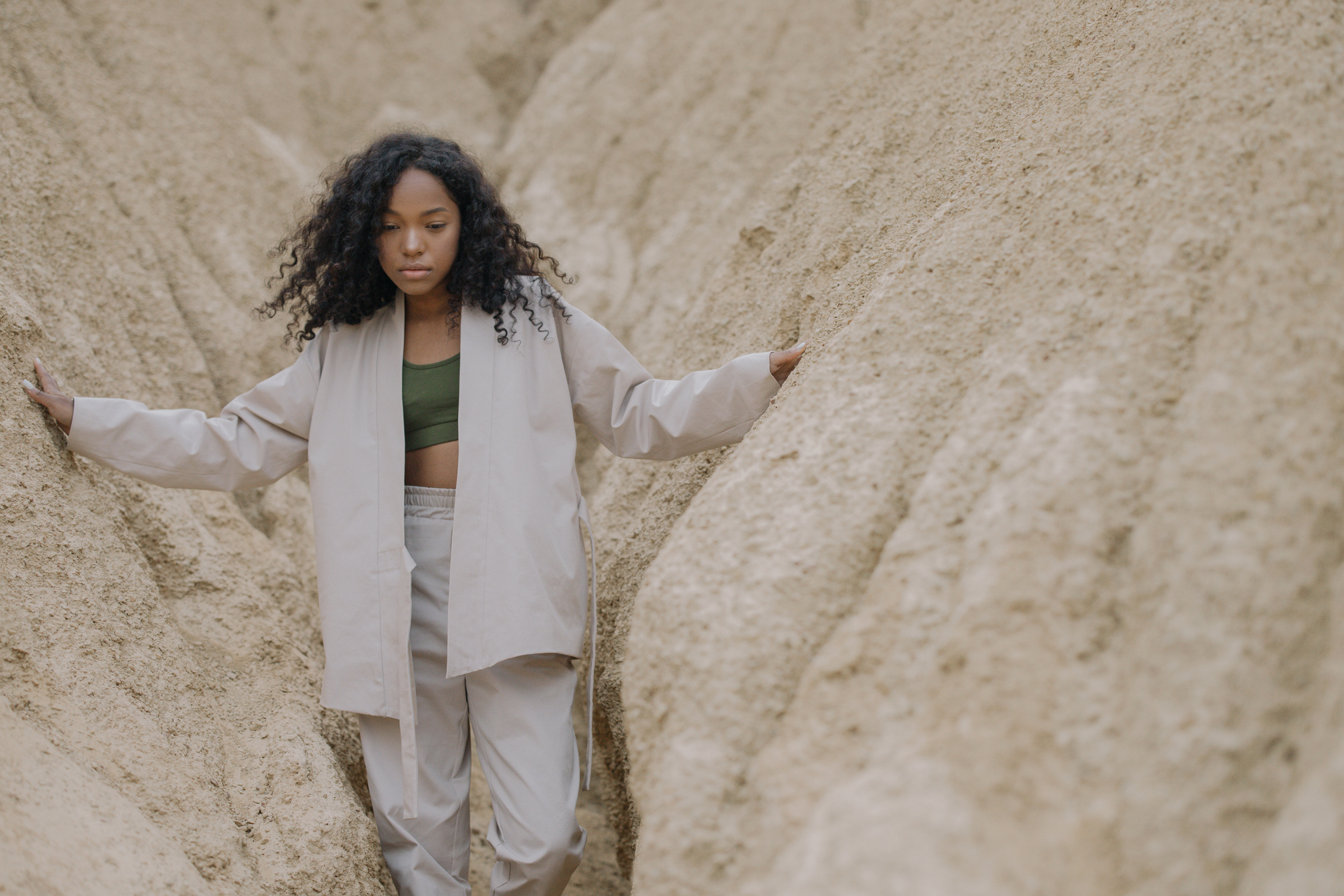 Woman in White Pajama Standing Between Brown Rough Walls